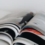 Vertical stack of open magazines showcasing various colorful pages in an artistic composition.